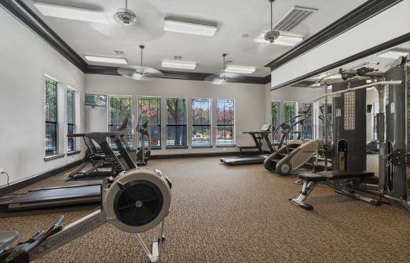a gym with weights and cardio equipment on the floor and windows