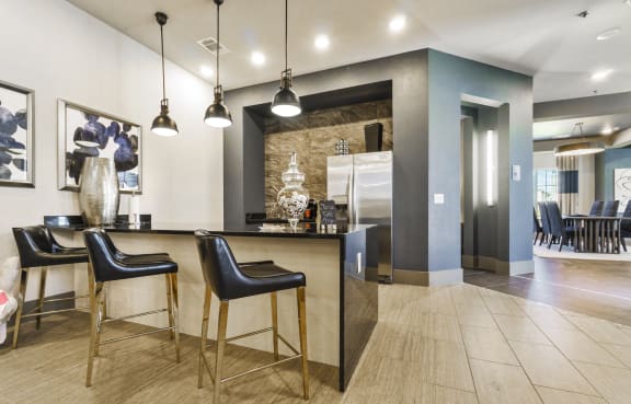 A modern kitchen with a bar area and black chairs.