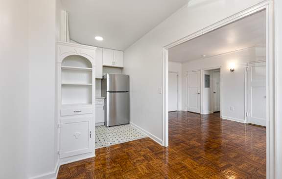 A kitchen with white cabinets and a wooden floor.