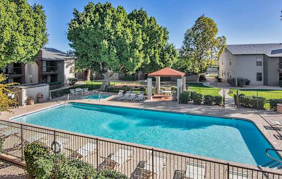 A swimming pool surrounded by a fence and trees.