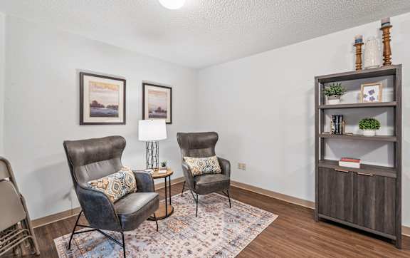 A clock hangs on a wall above a fireplace in a room.