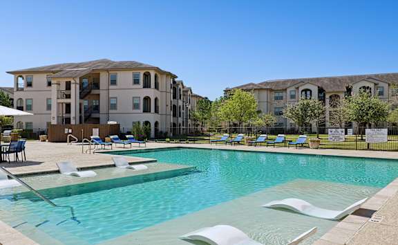 A swimming pool with a slide and a building in the background.