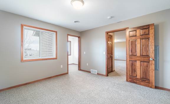 A room with a wooden door and a window with blinds.