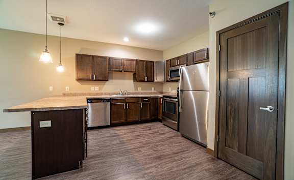 A kitchen with a stainless steel refrigerator and wooden cabinets.