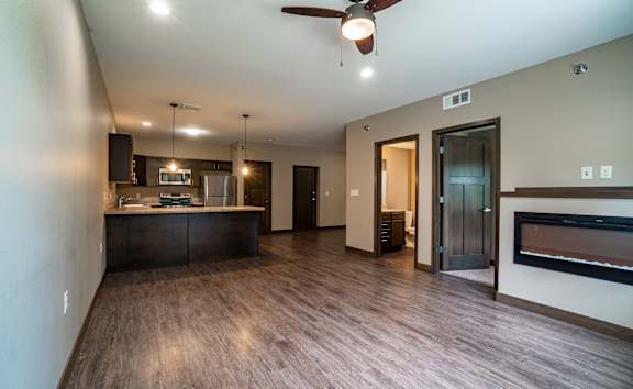 A modern kitchen with dark wood floors and a ceiling fan.