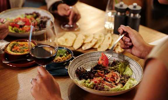 a group of people sitting around a table eating food and drinking