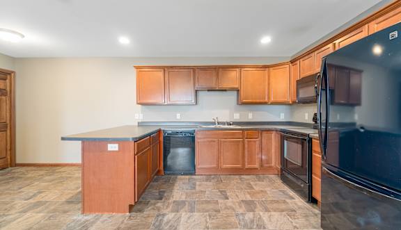 A kitchen with wooden cabinets and a black refrigerator.