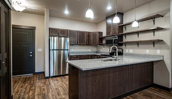 A kitchen with a stainless steel refrigerator and wooden floors.