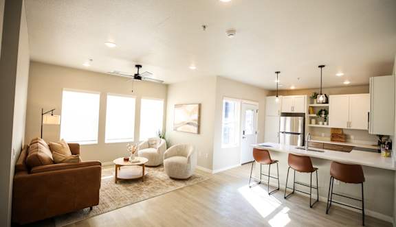 A modern kitchen with a brown couch and white chairs.