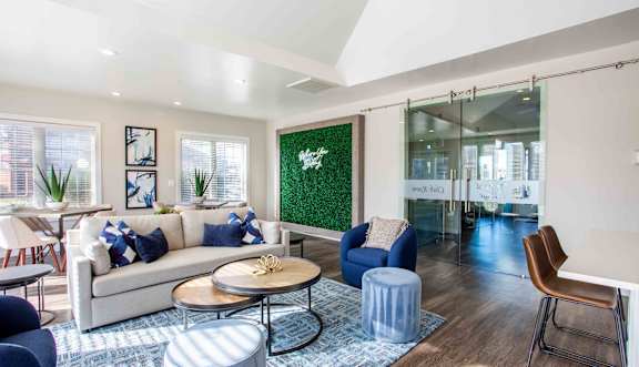 A living room with a white couch, blue ottoman, and a green wall.