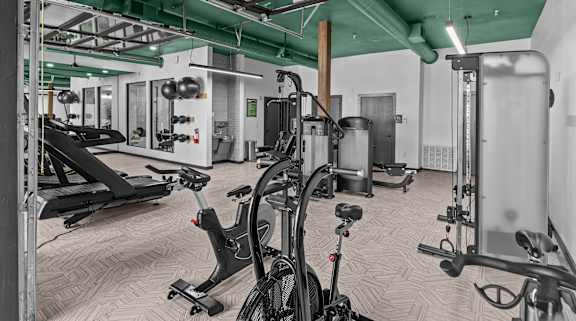 A gym with a variety of exercise equipment including treadmills, stationary bikes, and weight machines.
