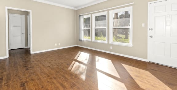 an empty living room with wood floors and windows