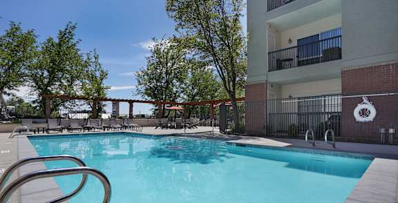 A swimming pool in front of a building with a red brick wall.