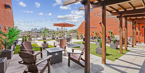A patio with wooden furniture and a red building in the background.