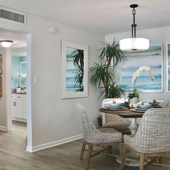 A dining room with a table set for two and a painting on the wall.