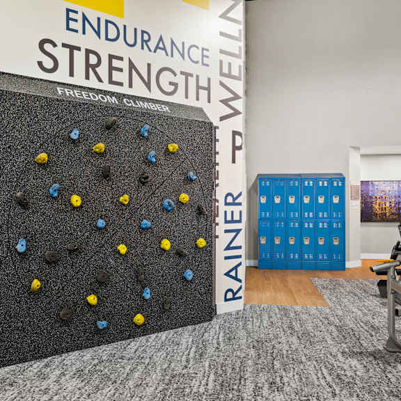 A climbing wall in a gym with a sign that says "Endurance Strength".