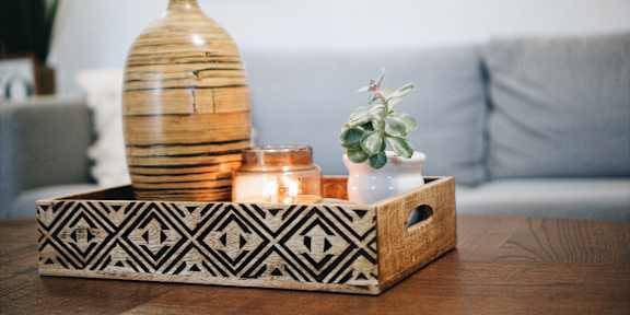 A decorative wooden box with a plant and candles on top of a vase.
