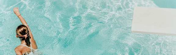 A pair of sunglasses is placed on the edge of a pool.