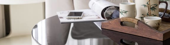 a living room with a couch and a table with coffee cups and a phone