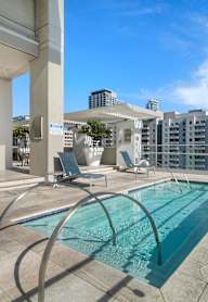 A modern pool area with a glass railing and a view of the city.