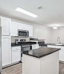A kitchen with white cabinetry, black stainless steel appliances and hard wood flooring