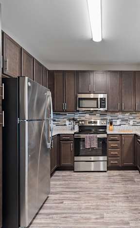 A modern kitchen with dark wood cabinets and stainless steel appliances.
