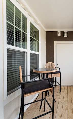 A balcony with a table and chairs overlooking a body of water.