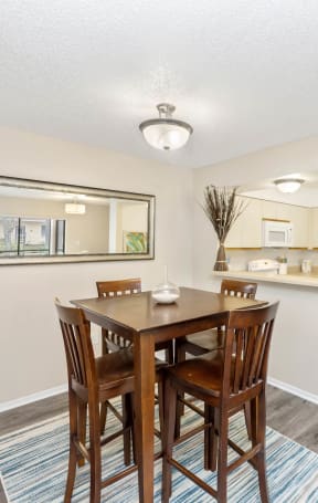 a dining area with a table and chairs and a kitchen in the background