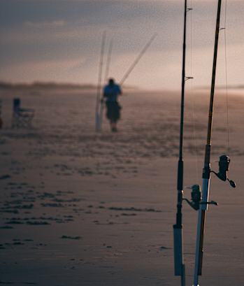 two fishing poles on the beach with a person standing in the distance