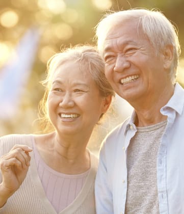an elderly couple standing in the sun with their arms around each other