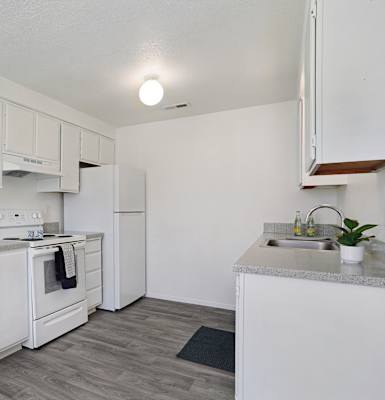 A white kitchen with a stove, oven, and sink.