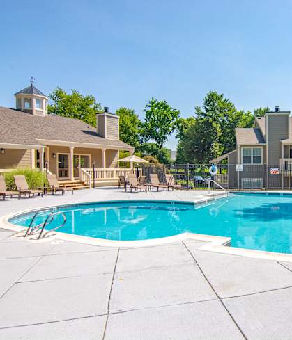 A large outdoor swimming pool surrounded by a white tile patio.