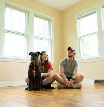 A man and a woman sitting on the floor with a dog.