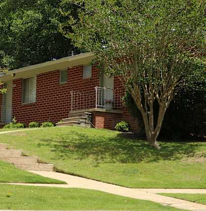 a red brick house with a tree in front of it