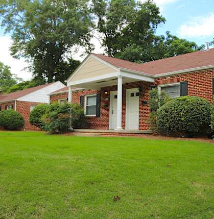 the front of a brick house with a green lawn