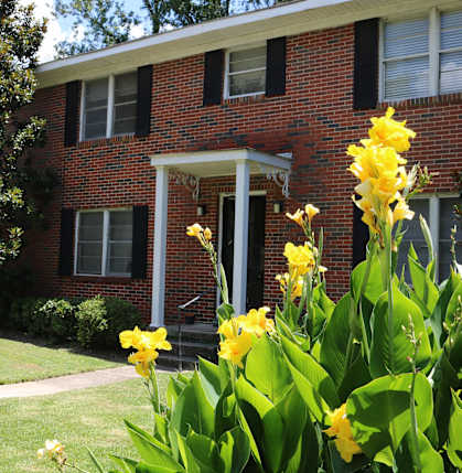 a red brick house with yellow flowers in front of it