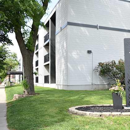 A grey sign with the number 151 on it in front of a building.