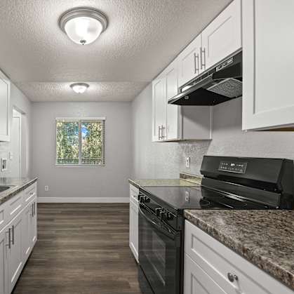 A kitchen with granite countertops and white cabinets.