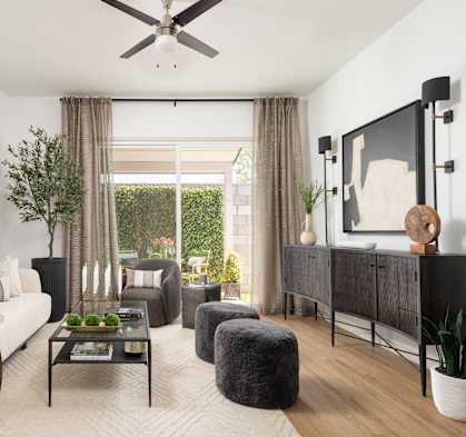 A living room with a white couch, a coffee table, and a large mirror on the wall.
