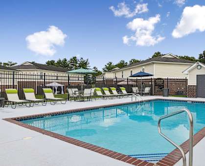 A large swimming pool surrounded by a fence and lounge chairs.