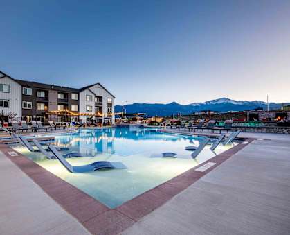 a swimming pool at night at a resort with mountains in the background