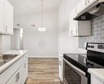 an empty kitchen with white cabinets and stainless steel appliances