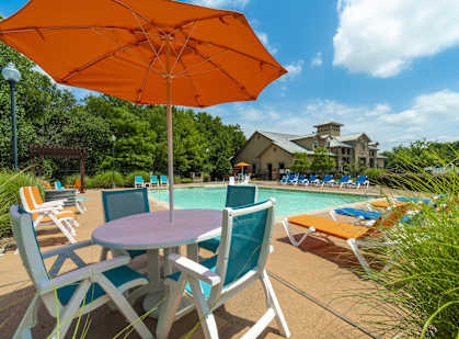 a table with chairs and an umbrella next to a swimming pool