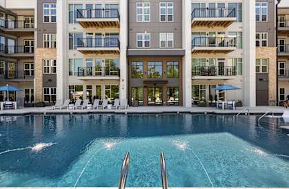 A large swimming pool in front of a multi-story apartment building.