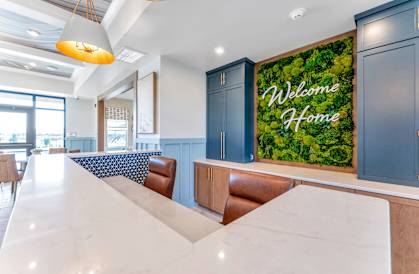 a kitchen with a counter and a table with chairs and a welcome home sign