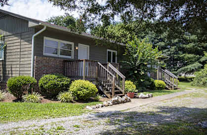 the front of a house with a porch and a sidewalk