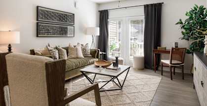 A living room with a couch, a chair, a coffee table, and a ceiling fan.