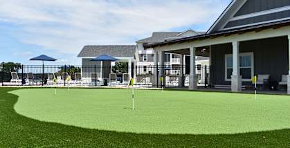 a putting green in front of a house with a clubhouse