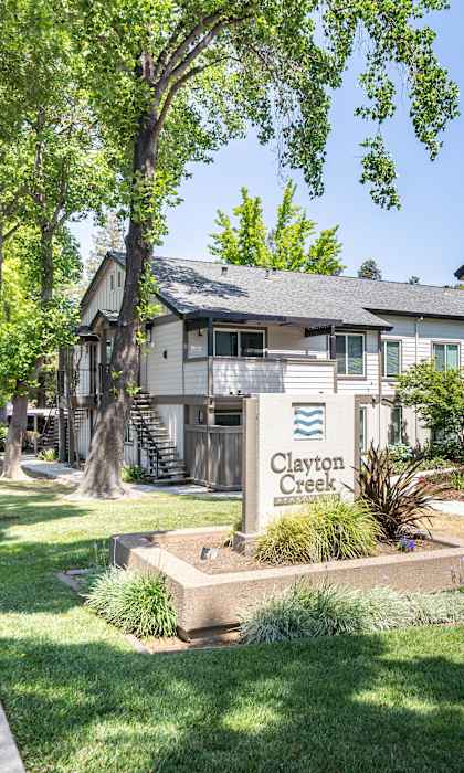 A row of houses with the name Clayton Creek on a sign in front.