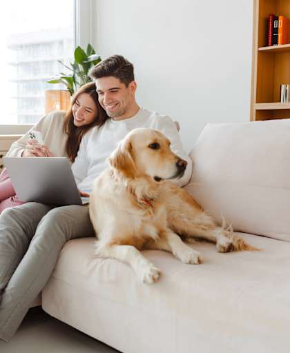 A man and woman sitting on a couch with a dog.